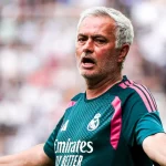 Pelatih berambut putih mengenakan seragam latihan Real Madrid berwarna hijau tosca merentangkan kedua tangan