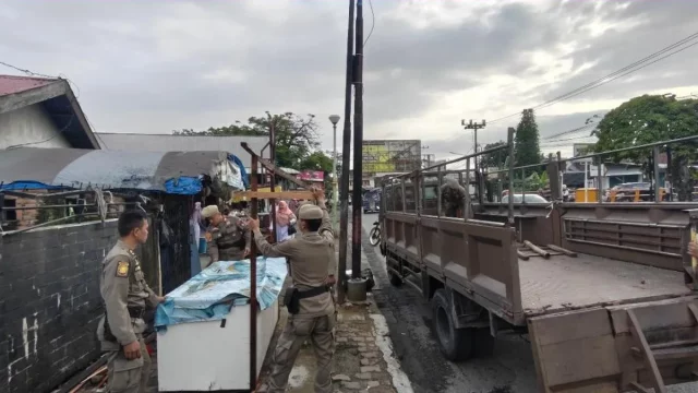 Petugas Satpol PP Kota Padang mengangkut lapak pedagang dari trotoar kawasan Pasar Alai