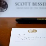 Catatan bertuliskan To Do Buy Japanese Yen di depan papan nama Scott Bessent