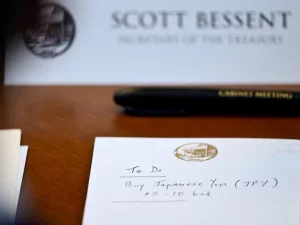 Catatan bertuliskan To Do Buy Japanese Yen di depan papan nama Scott Bessent