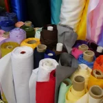 Gulungan kain aneka warna tersusun rapat dalam kotak di sebuah toko tekstil