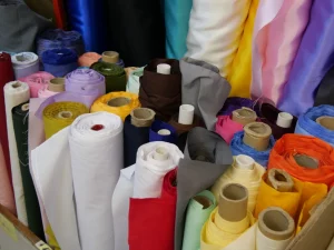 Gulungan kain aneka warna tersusun rapat dalam kotak di sebuah toko tekstil