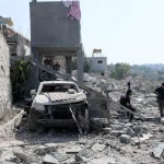 Warga memeriksa bangunan dan mobil yang hancur di desa Ansar, Lebanon selatan