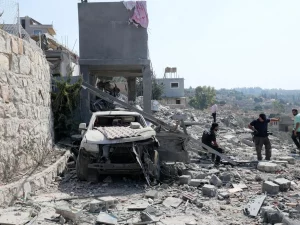 Warga memeriksa bangunan dan mobil yang hancur di desa Ansar, Lebanon selatan