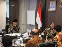 Sejumlah pejabat duduk mengelilingi meja rapat di ruang pertemuan kementerian dengan bendera Merah Putih dan lambang Garuda di dinding
