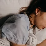 Seorang perempuan tidur berbaring di atas bantal putih