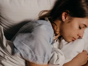 Seorang perempuan tidur berbaring di atas bantal putih