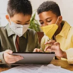 Ilustrasi dua siswa sekolah dasar membaca lewat tablet