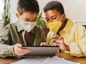 Ilustrasi dua siswa sekolah dasar membaca lewat tablet