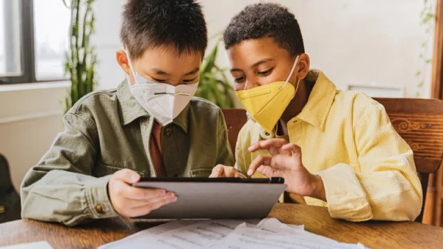 Ilustrasi dua siswa sekolah dasar membaca lewat tablet