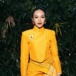Yura Yunita berpose mengenakan busana kuning dengan latar belakang tanaman hijau saat tampil di The Sounds Project
