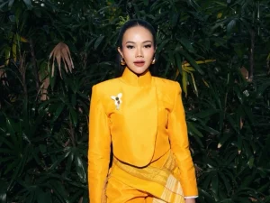 Yura Yunita berpose mengenakan busana kuning dengan latar belakang tanaman hijau saat tampil di The Sounds Project