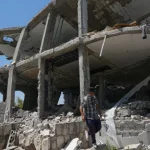 Seorang pria berjalan di antara reruntuhan rumah yang hancur di desa Zawtar al-Gharbiyah, Lebanon selatan