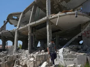 Seorang pria berjalan di antara reruntuhan rumah yang hancur di desa Zawtar al-Gharbiyah, Lebanon selatan