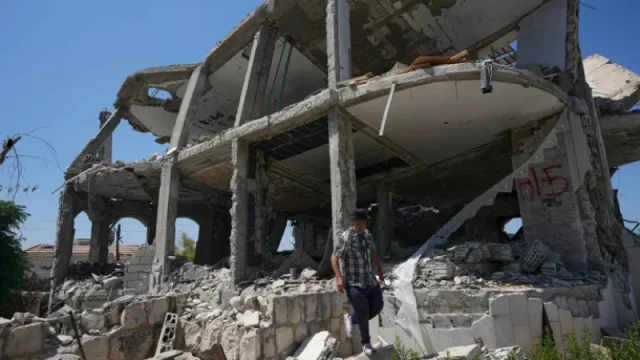 Seorang pria berjalan di antara reruntuhan rumah yang hancur di desa Zawtar al-Gharbiyah, Lebanon selatan