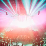 Ilustrasi suasana konser musik dengan lampu panggung warna-warni di arena, bukan foto konser Zico yang sebenarnya