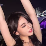 Zoe Levana mengangkat kedua tangan di area penonton LaLaLa Fest dengan panggung berlampu ungu di belakangnya.