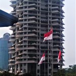 Ilustrasi gedung bertingkat berbendera Merah Putih di kawasan perkotaan Jakarta.