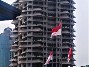 Ilustrasi gedung bertingkat berbendera Merah Putih di kawasan perkotaan Jakarta.
