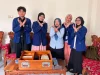 Lima orang berdiri di belakang meja kayu berisi dua kotak media pembelajaran sambil menyilangkan kedua tangan di depan dada.