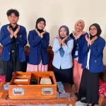 Lima orang berdiri di belakang meja kayu berisi dua kotak media pembelajaran sambil menyilangkan kedua tangan di depan dada.