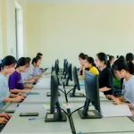 Sejumlah mahasiswa duduk berderet mengerjakan tugas di depan komputer dalam sebuah laboratorium.