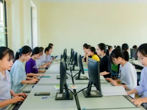 Sejumlah mahasiswa duduk berderet mengerjakan tugas di depan komputer dalam sebuah laboratorium.