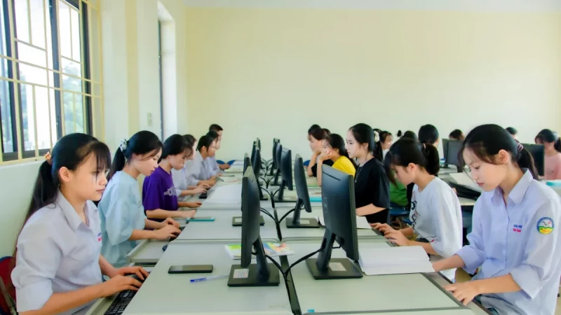 Sejumlah mahasiswa duduk berderet mengerjakan tugas di depan komputer dalam sebuah laboratorium.