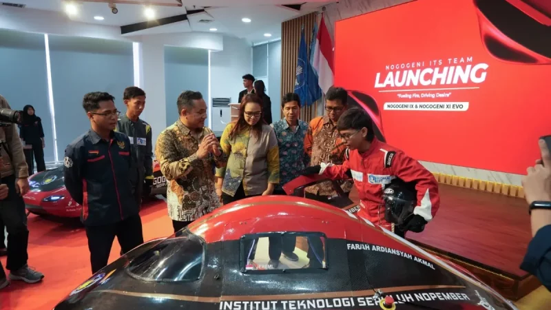 Sejumlah orang mengelilingi mobil hemat energi berwarna hitam dan merah di dalam ruangan berlatar layar bertuliskan Launching.