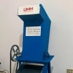 Mesin pencacah plastik berwarna biru dengan corong pemasukan di bagian atas berdiri di dalam ruangan.
