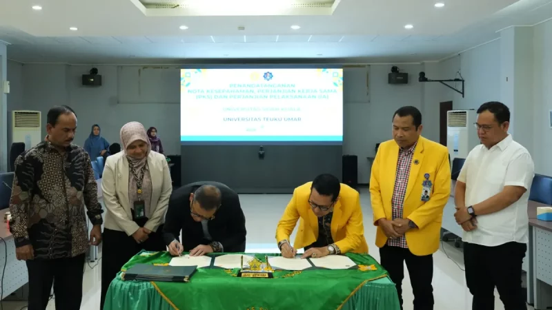 Dua rektor menandatangani dokumen di meja beralas kain hijau disaksikan enam pejabat di ruang rapat berlayar proyektor.