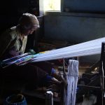 Seorang perempuan menenun hiou, kain tradisional Simalungun, pada alat tenun kayu.