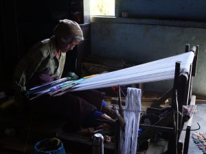 Seorang perempuan menenun hiou, kain tradisional Simalungun, pada alat tenun kayu.