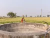Ilustrasi sebuah sumur terbuka bertembok beton di tepi ladang hijau
