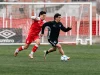 Dua pemain sepak bola beraksi di lapangan hijau