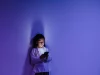 Seorang anak menatap layar ponsel yang menyala di ruangan berpencahayaan biru