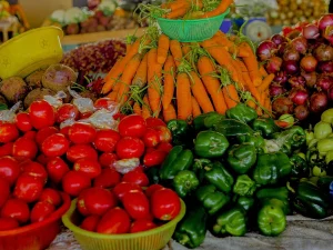 Tumpukan tomat, wortel, paprika hijau, bawang merah, dan terung Afrika di lapak pasar Rwanda