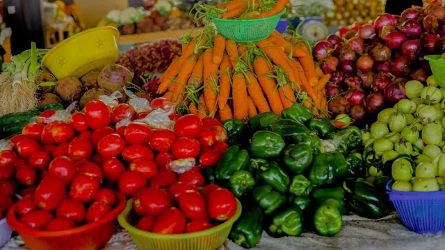 Tumpukan tomat, wortel, paprika hijau, bawang merah, dan terung Afrika di lapak pasar Rwanda