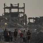Warga Palestina di antara reruntuhan bangunan yang hancur akibat serangan udara Israel di Kota Gaza
