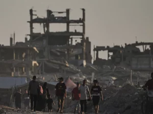 Warga Palestina di antara reruntuhan bangunan yang hancur akibat serangan udara Israel di Kota Gaza
