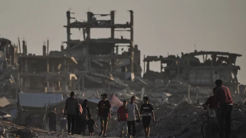 Warga Palestina di antara reruntuhan bangunan yang hancur akibat serangan udara Israel di Kota Gaza