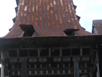 Atap menjulang dan fasad kayu berukir rumah adat Omo Nifolasara di Bawomataluo, Nias Selatan