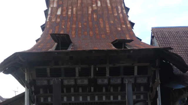 Atap menjulang dan fasad kayu berukir rumah adat Omo Nifolasara di Bawomataluo, Nias Selatan