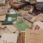 Tumpukan buku dan majalah lama berbahasa Indonesia di atas meja kayu dalam sebuah pameran arsip