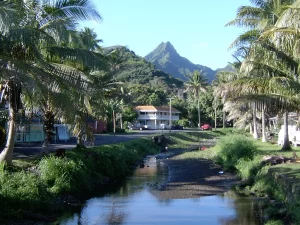 Sungai kecil diapit pohon kelapa dan rumah-rumah di Avarua, Rarotonga, Kepulauan Cook