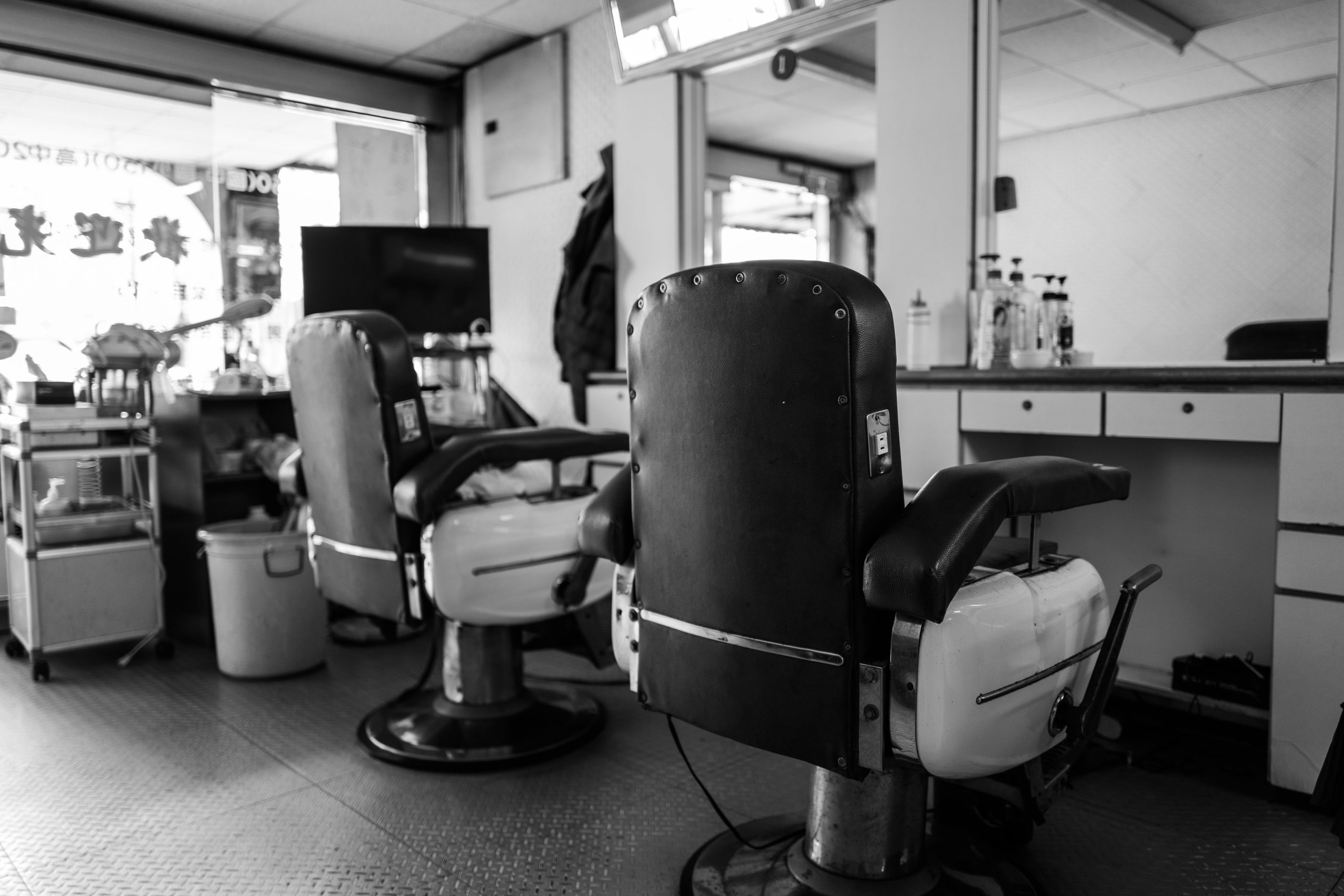 Ilustrasi interior pangkas rambut lawas dengan deretan kursi cukur klasik.