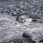 Air banjir keruh mengalir deras di antara bongkahan batu Grand Canyon