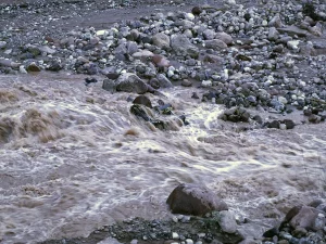 Air banjir keruh mengalir deras di antara bongkahan batu Grand Canyon