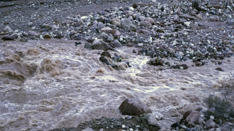 Air banjir keruh mengalir deras di antara bongkahan batu Grand Canyon