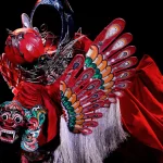 Barong Kemiren bersayap dan bermahkota merah dalam sebuah pertunjukan di panggung gelap